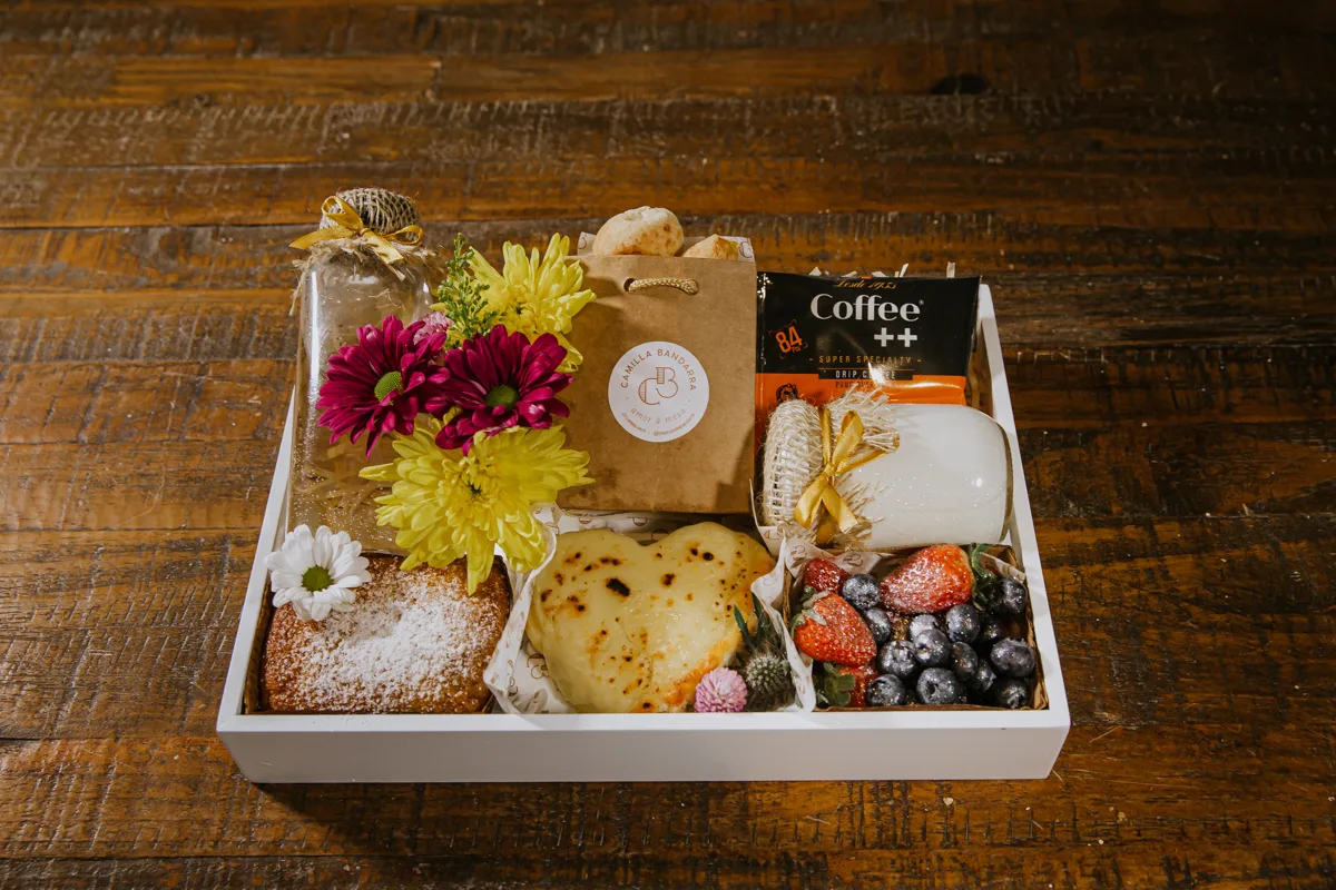 Caixa de café da manhã com flores, bolo, pão na chapa, frutas vermelhas e café especial