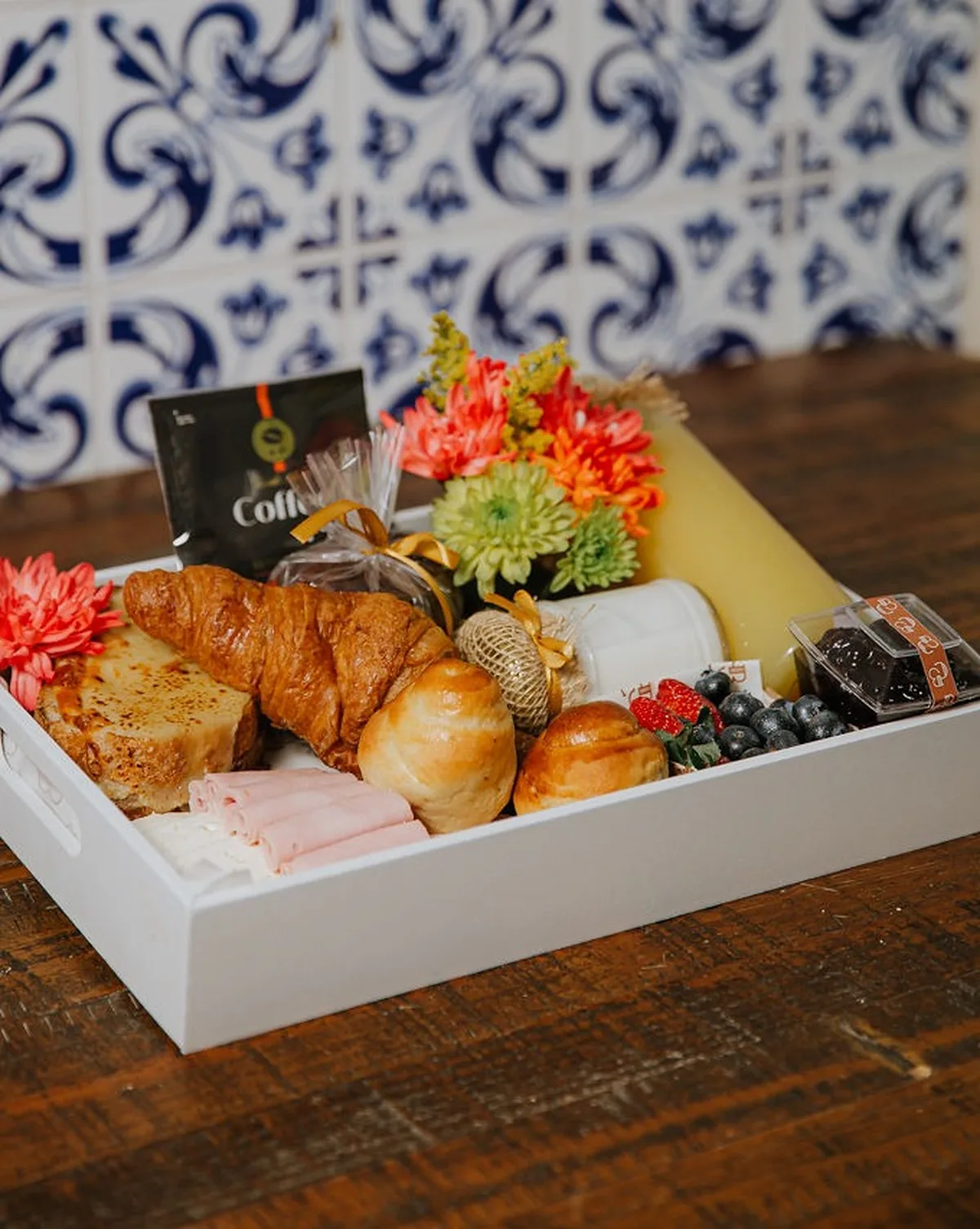 Bandeja de café da manhã com croissant, pães, frutas, flores e suco
